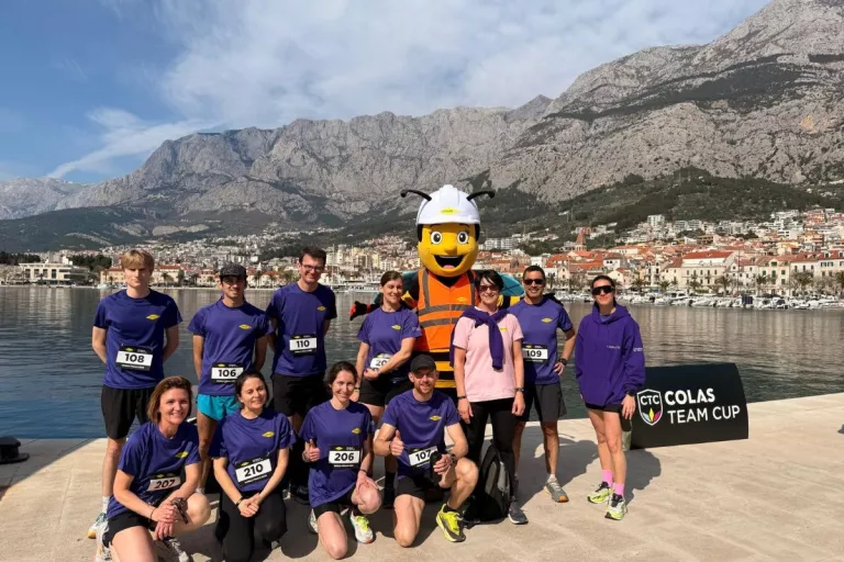 collaborateurs Colas en violet avec des montagnes en arrière plan et une mascotte