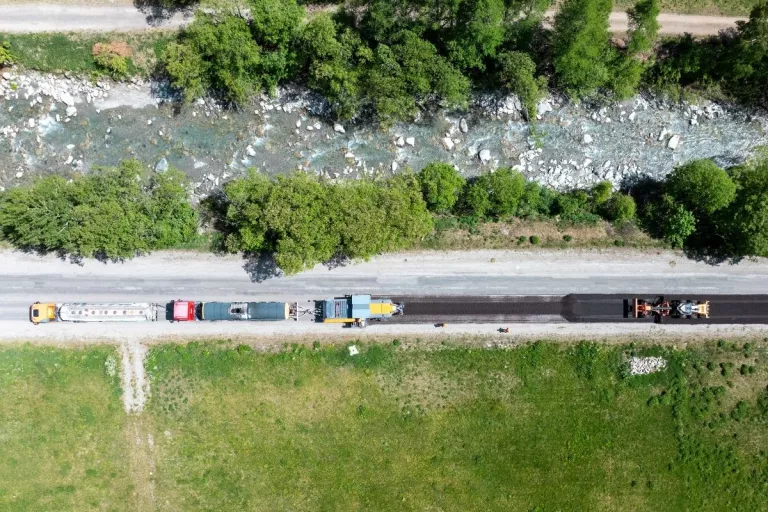 Vue aérienne du chantier Recycol à Bonneval-sur-Arc montrant les engins de recyclage de la chaussée et le cours d'eau voisin.