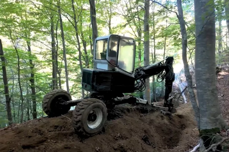 Engin de chantier réalisant des travaux de terrassement sur une pente boisée