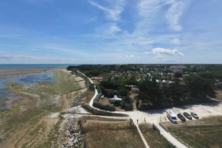 Vue aérienne d’un cheminement longeant le littoral et desservant une zone arborée.