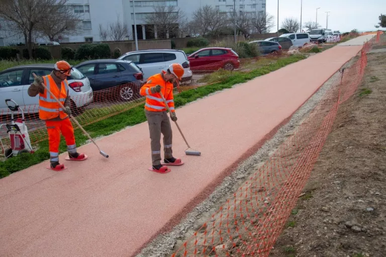 Deux ouvriers réalisent le revêtement rouge d’une nouvelle piste cyclable à Port-de-Bouc.