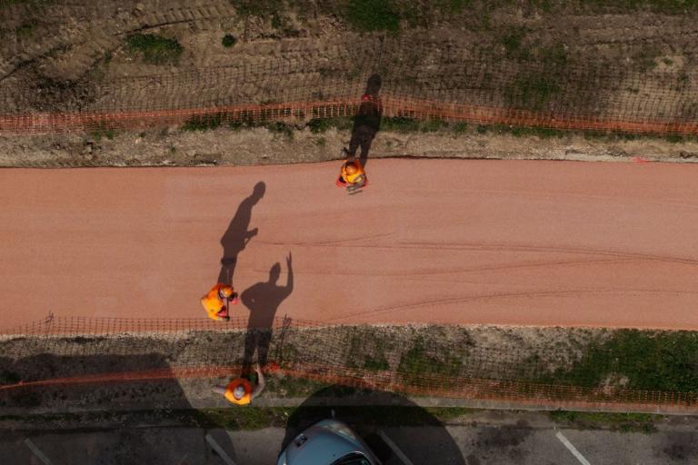 Vue aérienne de trois ouvriers intervenant sur le revêtement d’une piste cyclable.