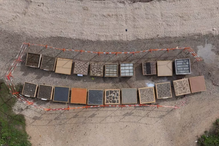 Vue aérienne de plusieurs revêtements de sol expérimentaux présentés dans des cadres sur une zone de chantier