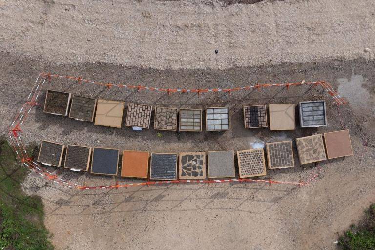 Vue aérienne de plusieurs revêtements de sol expérimentaux présentés dans des cadres sur une zone de chantier