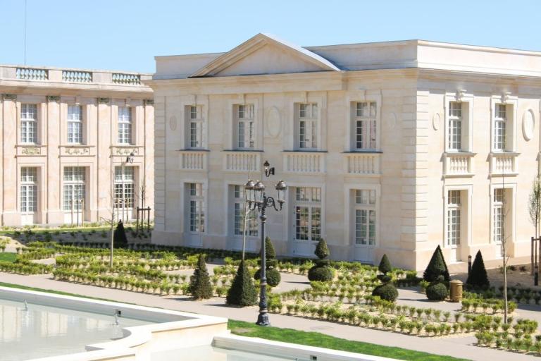 Façade en pierre claire, jardins structurés et bassin dans un espace paysager d’inspiration classique au Puy du Fou.