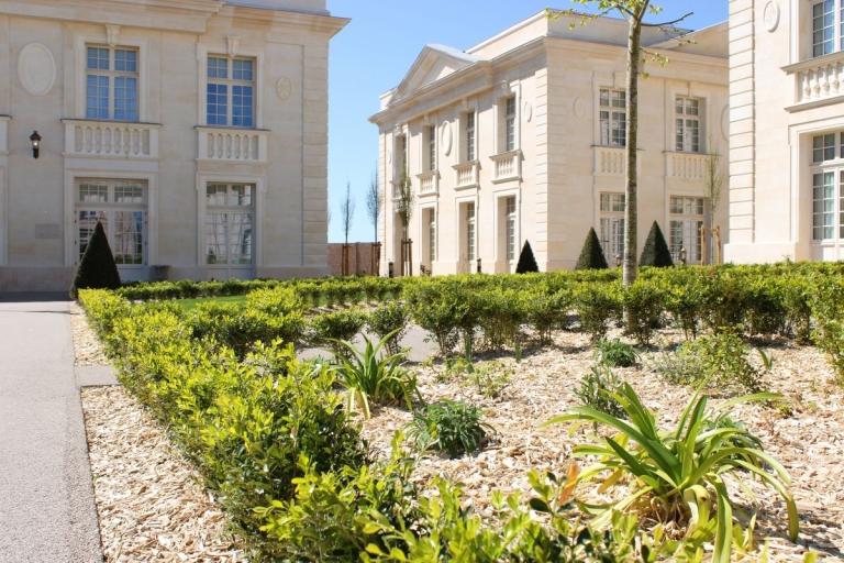 Jardins à la française du Puy du Fou avec haies taillées, plantations paysagères et façades en pierre de style classique.