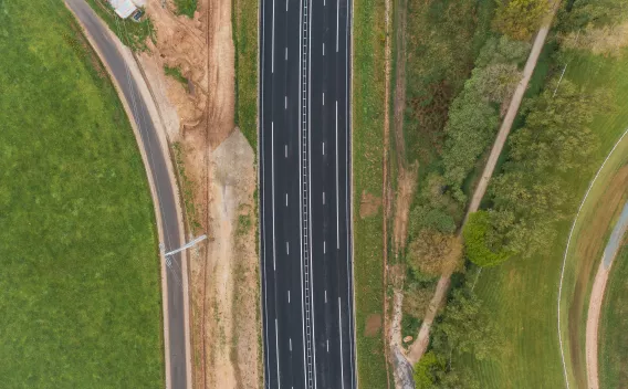 Réfection complète d’une piste aéroportuaire au crépuscule : marquages neufs, balisage lumineux en service et engins en intervention le long des accotements.
