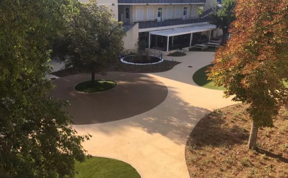 Jardin apaisé en site urbain, circulations douces en enrobé clair, intégration paysagère soignée autour des espaces verts.