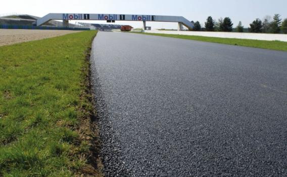 Une piste fraîchement asphaltée s’étire vers un pont brandissant la signalétique Mobil 1, prête pour la vitesse et la performance.