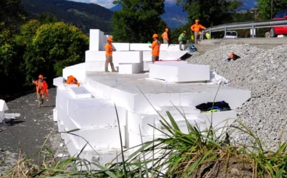 Remblai allégé en blocs de polystyrène expansé posé en talus sous contrôle d’équipe, pour stabiliser une plateforme routière en terrain compressible.