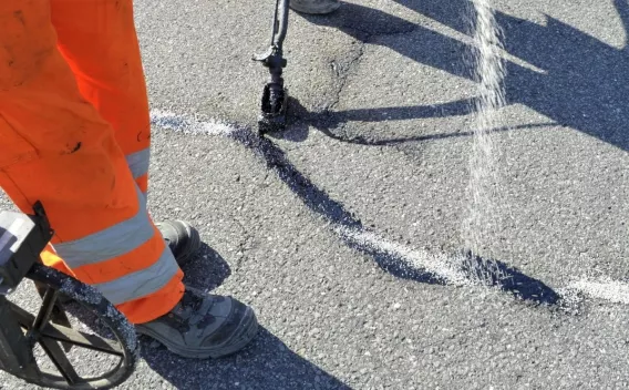 En plein soleil, un agent en orange scelle une fissure au trait blanc, prolongeant la vie de la route.