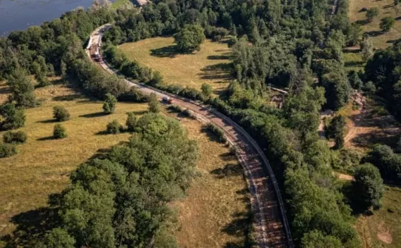Réhabilitation d’une route sinueuse en milieu naturel avec gestion des berges et pose d’enrobés pour assurer stabilité et drainage.