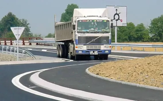 Intersection routière récemment revêtue en enrobé avec marquages définitifs et bordures en béton — solution garantissant endurance au trafic poids lourd et sécurité des manœuvres.