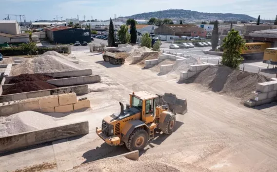 Valormat plateforme de recyclage : Vue aérienne d’un chantier de terrassement et soutènement en zone résidentielle montrant palplanches en place, terrassement en cours, engins de fouille et de compactage, signalisation et zones de stockage.