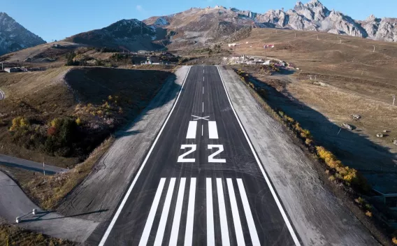 Altiport de Courchevel : Piste de montagne fraîchement resurfacée, marquages 22 nets et contrastés, intégrée dans un paysage alpin pour des opérations aériennes sûres en environnement exigeant.