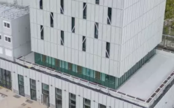 Construction de Bâtiment par Colas : Vue aérienne d’un bâtiment tertiaire moderne avec toiture technique et façades blanches, entouré d’espaces extérieurs et d’un parking.