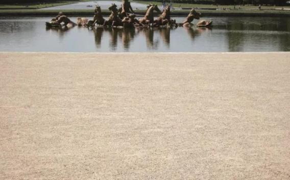  Bassin et groupe sculpté en avant-plan avec allée gravillonnée et perspective aquatique bordée de haies, atmosphère calme.