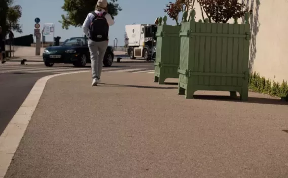 Équipe en tenue de sécurité procédant à la mise en œuvre d’un revêtement piétonnier sur trottoir, avec matériel de chantier et balisage.