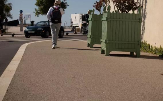 Équipe en tenue de sécurité procédant à la mise en œuvre d’un revêtement piétonnier sur trottoir, avec matériel de chantier et balisage.