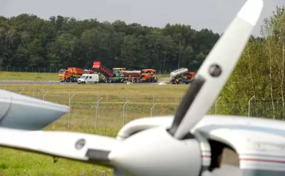 Intervention sur piste aéroportuaire avec engins spécialisés et camions en opération.