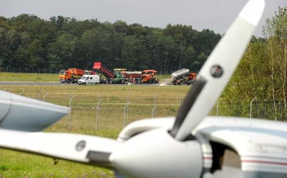 Intervention sur piste aéroportuaire avec engins spécialisés et camions en opération.