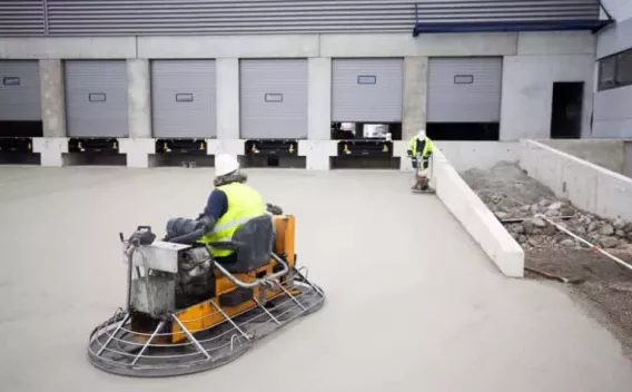 Finition mécanique d’un dallage béton sur site logistique, assurant planéité et haute résistance.