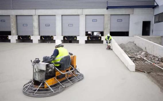 Finition mécanique d’un dallage béton sur site logistique, assurant planéité et haute résistance.