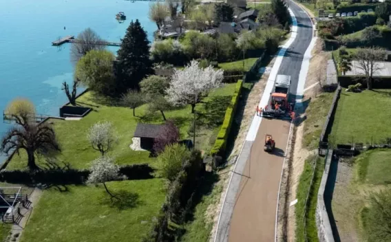 Application et compactage d’un revêtement routier/piétonnier en milieu périurbain avec équipes en EPI, engins d’enrobage et compactage, zone de chantier balisée et préparation d’accotements.