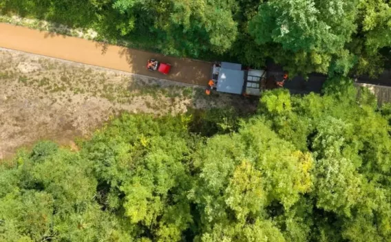 Réfection de voirie en milieu boisé : pose d’un revêtement perméable coloré pour une piste cyclable/piétonne, réalisation par compactage mécanisé avec guidage précis, bordures et emmarchements respectant l’environnement immédiat.