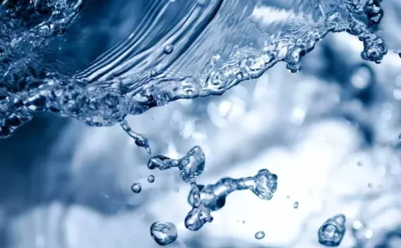 Gros plan dynamique de gouttes d'eau en suspension, capturant la fluidité, la transparence et les reflets bleutés dans un mouvement cristallin.