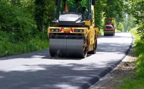 Compacteur en action sur une chaussée fraîchement asphaltée, assurant une finition lisse et conforme aux standards de sécurité routière.