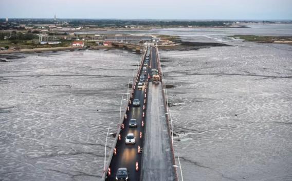 Travaux de nuit sur un pont : circulation alternée, balisage et reprise de la chaussée par chaussée partiellement fraîchement revêtue.