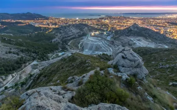 Carrière de Saint-Tronc près de Marseille : Vue aérienne d’un chantier de soutènement le long d’une voie résidentielle, montrant palplanches installées, terrassement et engins en action avec signalisation et stockage sur site.