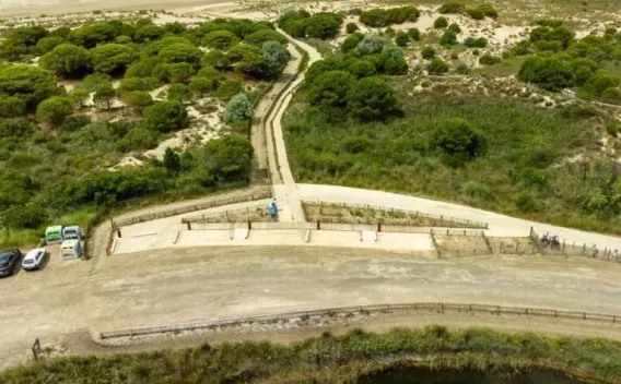 Deux techniciens en EPI supervisent la pose et le compactage d’un enduit de chemin au niveau d’un accès côtier, assurant la protection des abords et la continuité de la liaison piétonne.