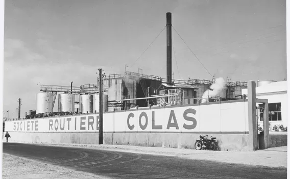 Archives photo historique Colas : Vue aérienne d’un chantier de soutènement et terrassement entre maisons avec palplanches, deux pelles, compacteur et zones de stockage.