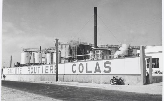 Archives photo historique Colas : Vue aérienne d’un chantier de soutènement et terrassement entre maisons avec palplanches, deux pelles, compacteur et zones de stockage.