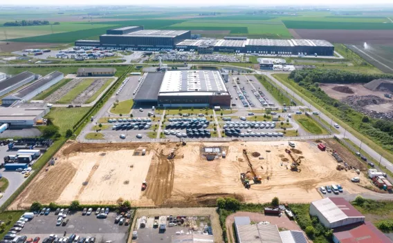Création d_un parking VL pour Amazon - Lille : Terrassement de grande emprise sur parcelle industrielle en cours : surface nivelée, engins de terrassement répartis et voies d'accès préparées pour futur bâtiment logistique.