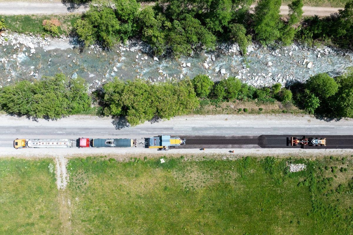 Vue aérienne du chantier Recycol à Bonneval-sur-Arc montrant les engins de recyclage de la chaussée et le cours d'eau voisin.