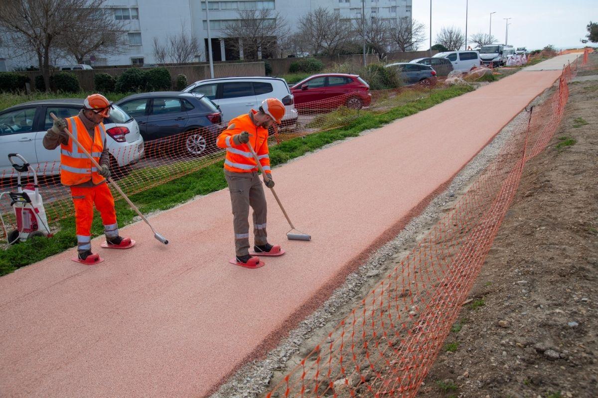 Deux ouvriers réalisent le revêtement rouge d’une nouvelle piste cyclable à Port-de-Bouc.