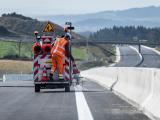 Un opérateur applique le marquage blanc sur le bord de la chaussée à l’aide d’un véhicule spécialisé sur une section d’autoroute en construction