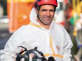 Intervention HSE sur chantier mobile, opérateur en combinaison étanche, casque et gants, manipulant un masque intégral pour opérations spécifiques en environnement contrôlé.