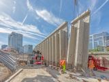 Montage de panneaux préfabriqués en béton sur chantier urbain avec grue et ouvriers en haute visibilité ajustant les éléments.