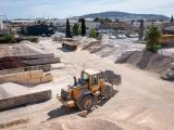 Vue aérienne d'une carrière en terrasses bordée de végétation, avec zones de concassage et de stockage organisées en pied de site et voies d'accès clairement tracées.