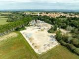 Vue aérienne d’une carrière/recyclerie et d’une centrale d’enrobés avec aires de stockage de granulats triés en cônes, voies d’accès et zone logistique prête à l’approvisionnement.
