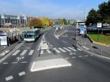 Aménagement urbain : carrefour organisé avec voies bus et arrêts structurés, bandes cyclables marquées, traversées piétonnes et îlots de refuge pour sécuriser les circulations multimodales et faciliter l’accès aux transports en commun.