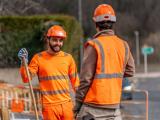Équipe voirie en coordination sur chantier routier, EPI complets haute visibilité, dialogue opérationnel au pied des zones balisées pour une exécution sûre et efficace.