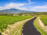 Réfection route d'accès Mont Ventoux par Colas : Route campagnarde fraîchement revêtue serpentant entre vignobles et collines, illustrant qualité d’ouvrages routiers, intégration paysagère et accessibilité rurale.