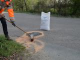 Page d’erreur Colas en haut, puis photo d’un agent en gilet orange balayant un absorbant sur une fuite sur la chaussée près d’un sac blanc — composition claire et professionnelle.