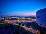 Création du tablier du pont Simone Veil à Bordeaux par Colas : Vue nocturne d’un aménagement urbain riverain éclairé : pont, voies piétonnes et espace public aménagé le long de l’eau.