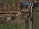 Chantier d’excavation en plein champ avec pelles et blindage installés pour creuser une tranchée de réseau.